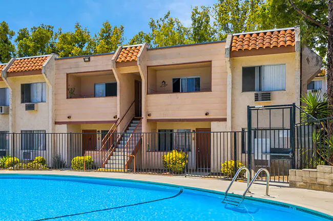 Hillside apartment complex with terracotta roof and pool amenities