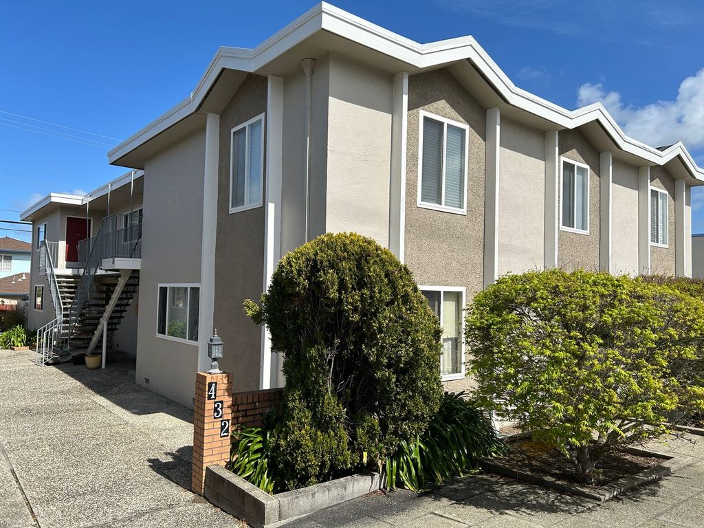 Modern stucco apartment building with professional landscaping and signage