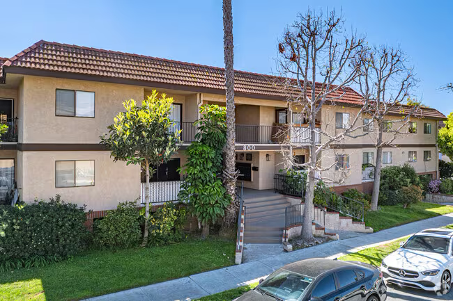 Stucco apartment complex with central staircase and front lawn