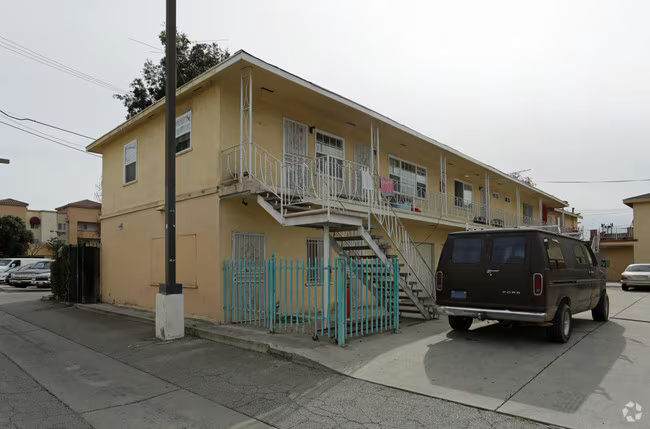 Yellow stucco duplex with exterior staircase and street parking