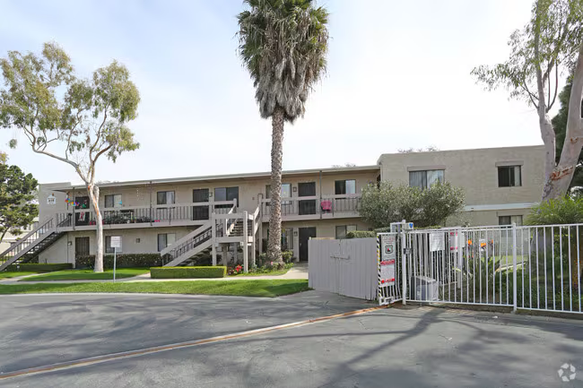 Large apartment complex with gated entry and palm-lined courtyard