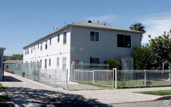 White two-story multifamily with perimeter fence and corner lot