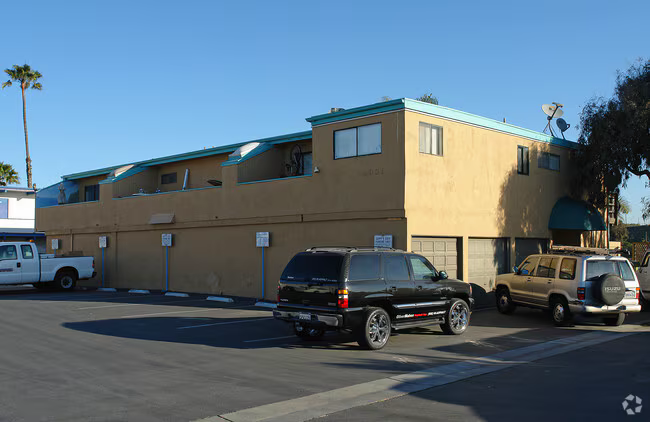 Tan stucco apartment building with teal accents and covered parking